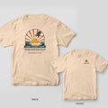 Back and front of an ivory T-shirt: back shows a heron flying across a marsh sunrise above a First Light Club banner; front has a small tail and sun logo