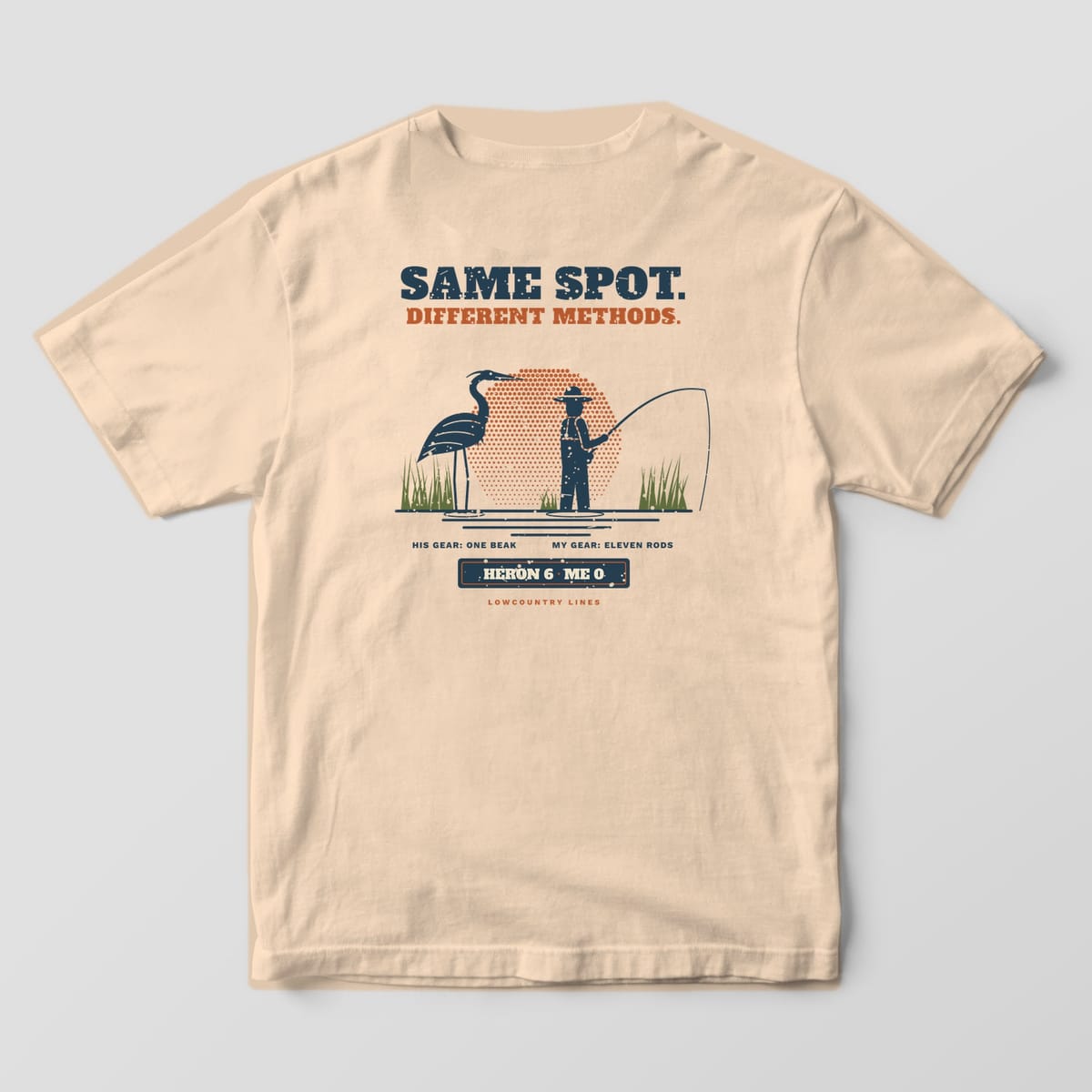 Ivory Comfort Colors tee, back view, with a navy heron and angler scene, copper halftone sun and a Heron 6, Me 0 scoreboard