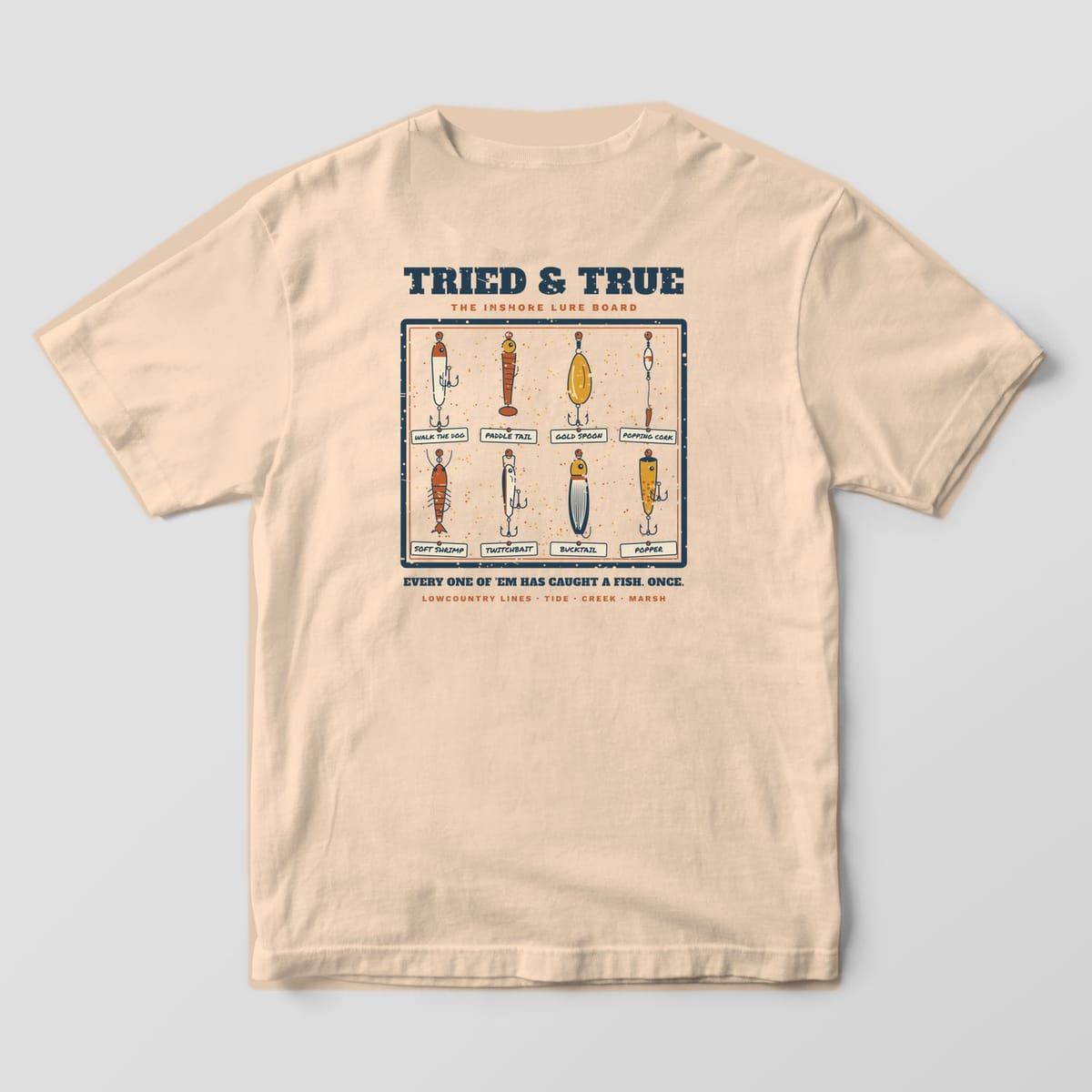 Ivory Comfort Colors tee, back view, with a cork lure board of eight hand-drawn inshore lures with handwritten tags