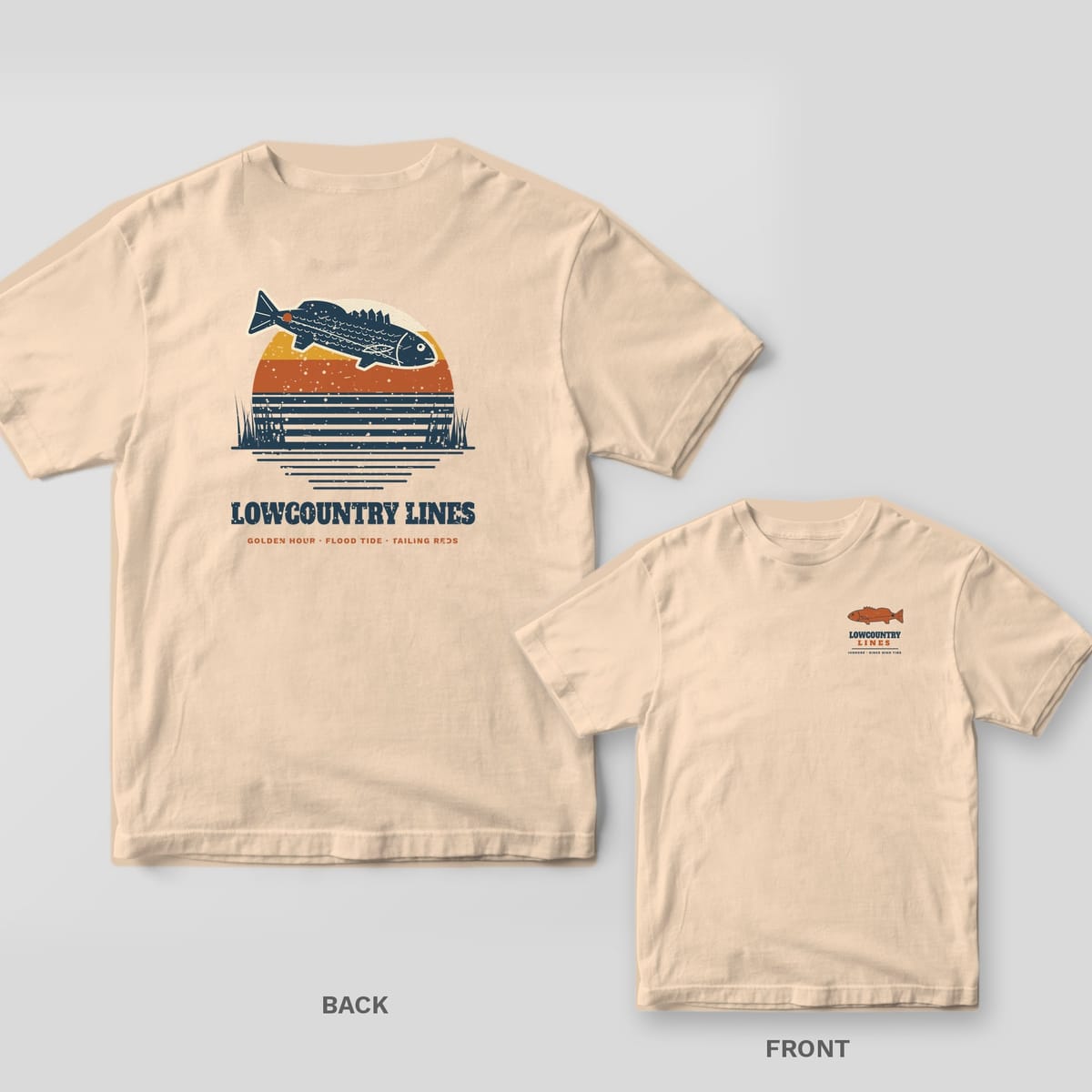 Back and front of an ivory T-shirt: back shows a navy redfish leaping over a retro striped sunset; front has a small copper redfish logo