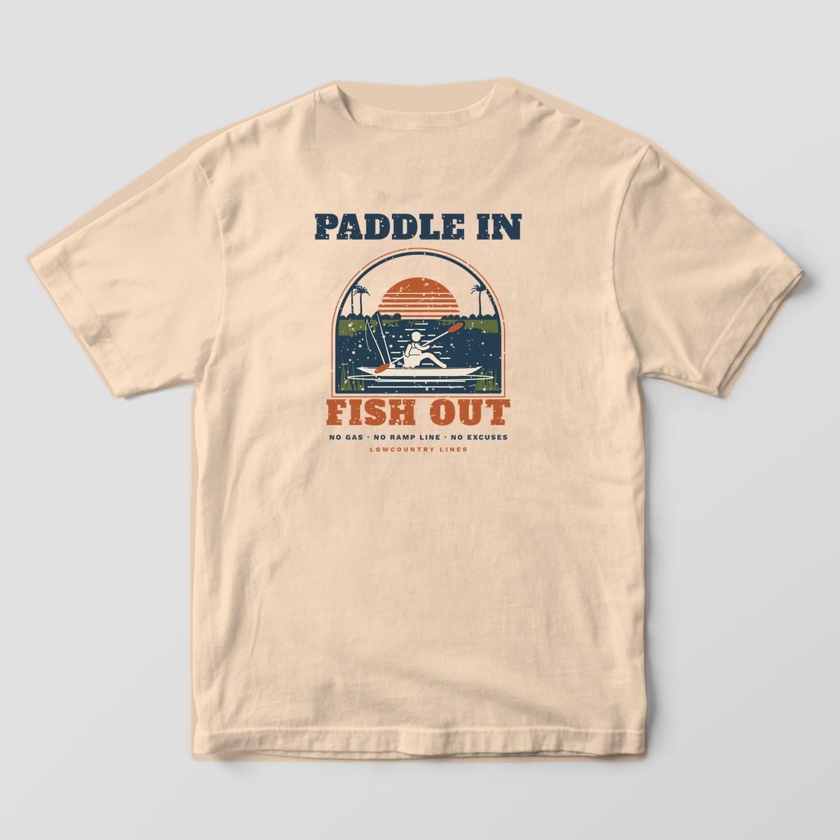 Ivory Comfort Colors tee, back view, with a cream kayak angler on a navy creek, copper sun, palmettos and olive marsh grass