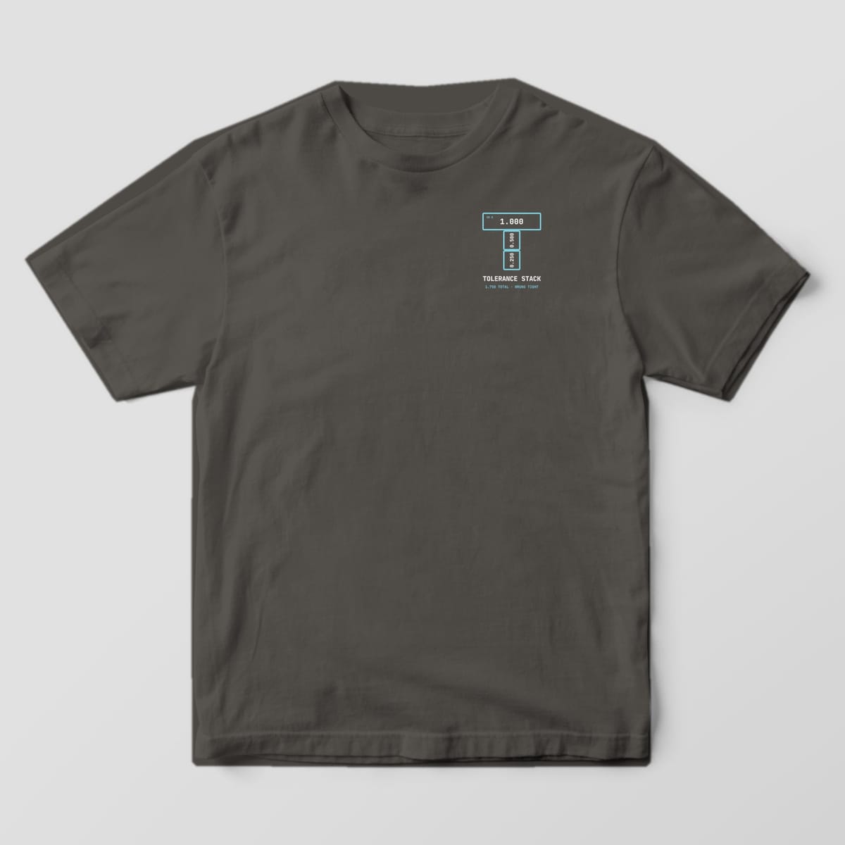 Front of a Pepper Comfort Colors 1717 tee with a small left-chest letter T made of three gauge blocks above the words Tolerance Stack.