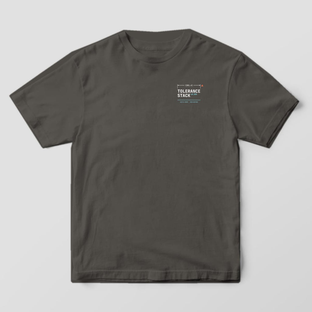 Front of a Pepper Comfort Colors 1717 tee with a small left-chest Tolerance Stack wordmark under a dimension line with a warning triangle.