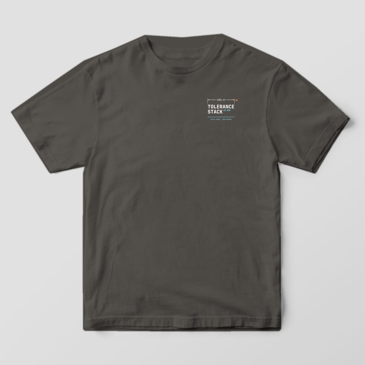 Front of a Pepper Comfort Colors 1717 tee with a small left-chest Tolerance Stack wordmark under a dimension line with a warning triangle.