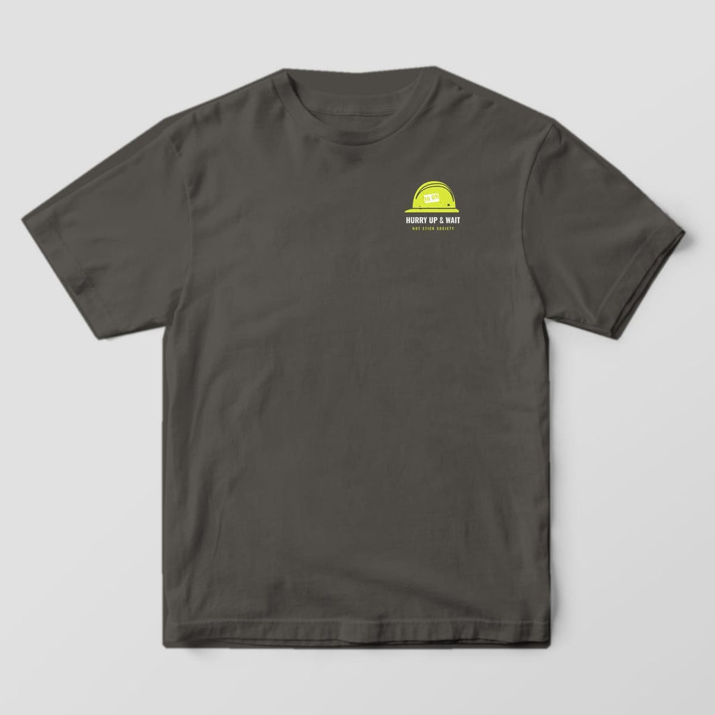 Front view of the pepper Comfort Colors 1717 shirt with the small left-chest Hurry Up and Wait Storm Time Card print