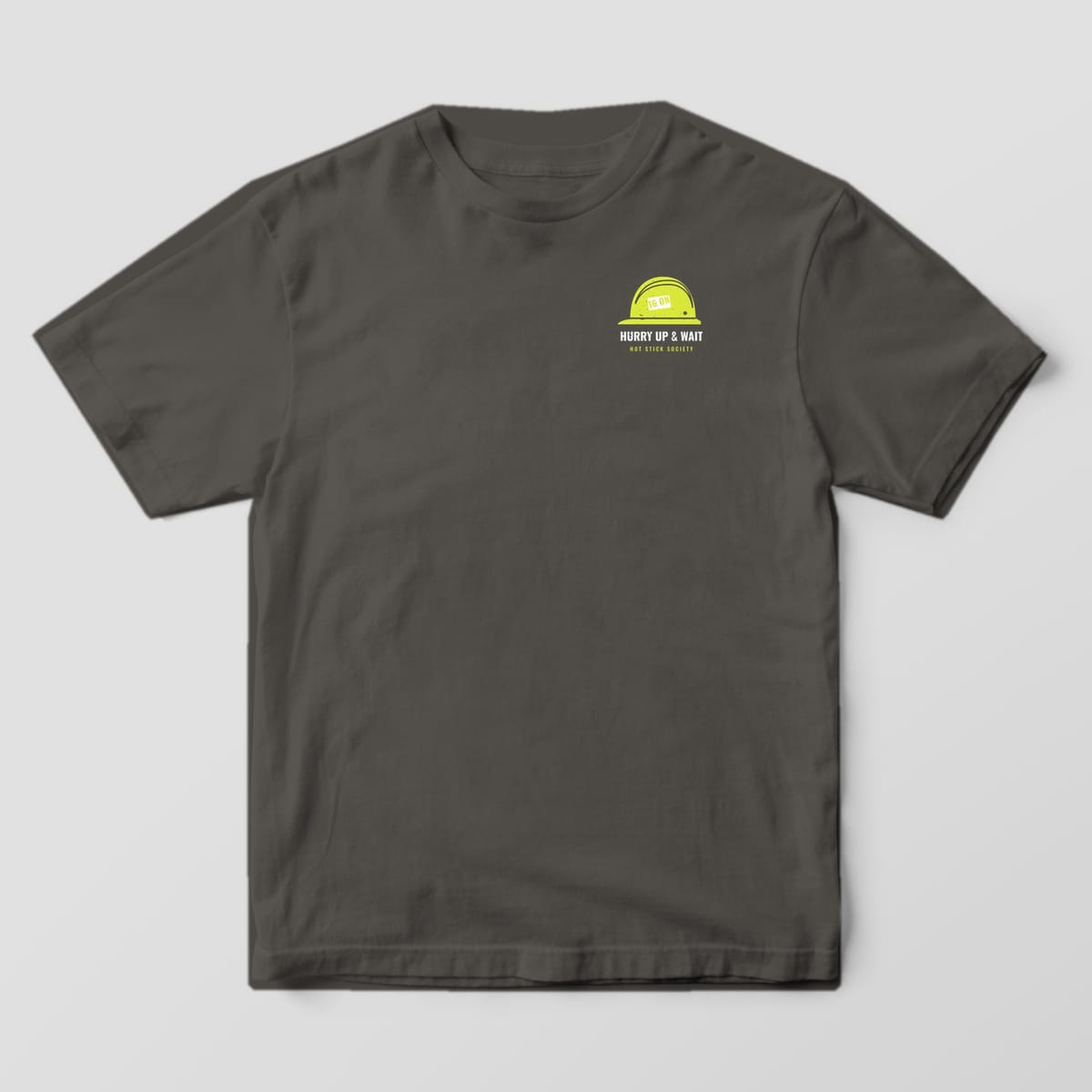 Front view of the pepper Comfort Colors 1717 shirt with the small left-chest Hurry Up and Wait Storm Time Card print
