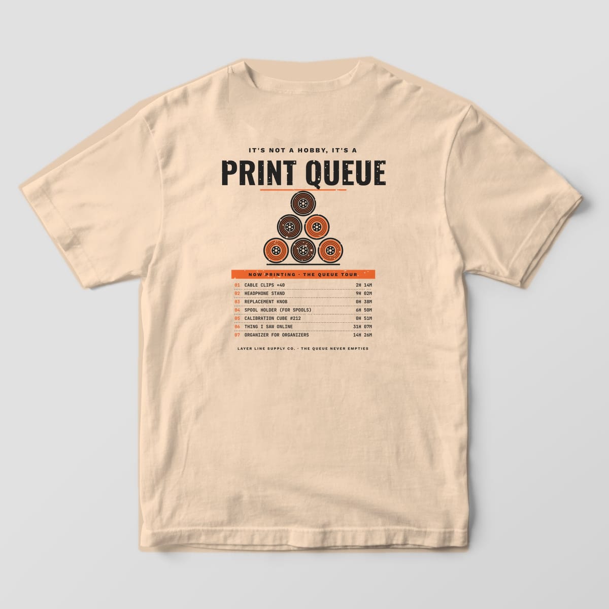 Back print on an Ivory Comfort Colors 1717 tee: "It's Not a Hobby, It's a Print Queue" over a pyramid of six orange and charcoal spools, with a seven-item Now Printing queue list and print times