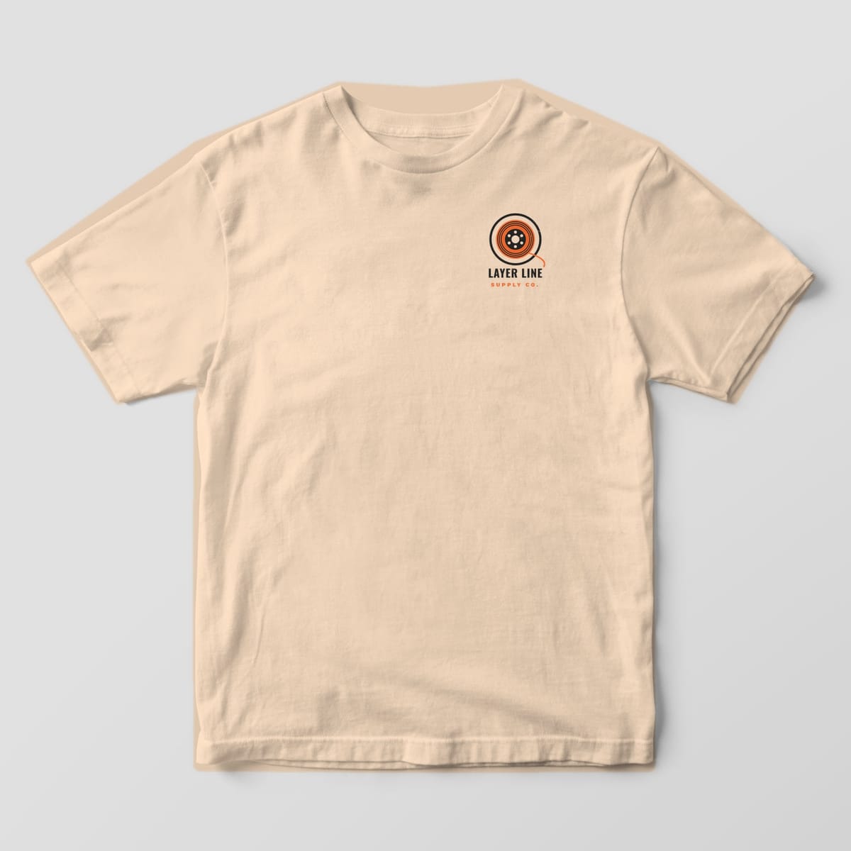 Front of the Ivory Comfort Colors 1717 tee showing the left-chest print: Small left-chest Layer Line spool logo with a loose filament tail and the "Layer Line Supply Co." wordmark