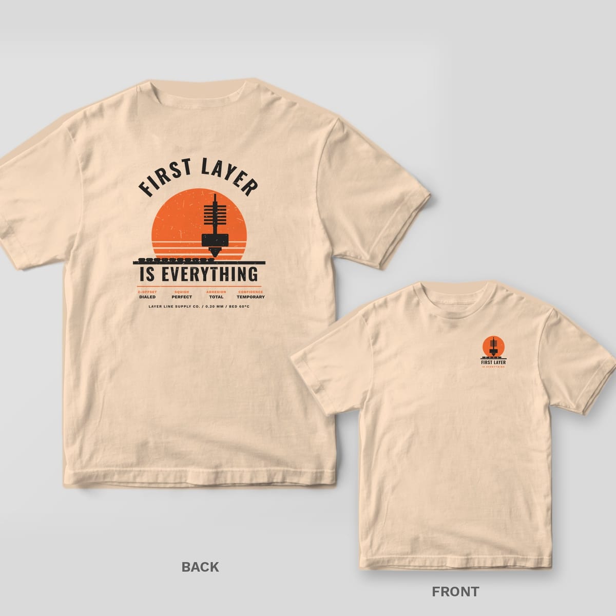 First Layer Is Everything 3D printing shirt shown back and front on Ivory Comfort Colors 1717: Arched "First Layer" over a striped orange sunset and nozzle laying down a perfect first layer, "Is Everything" below, with a spec row: Z-offset…
