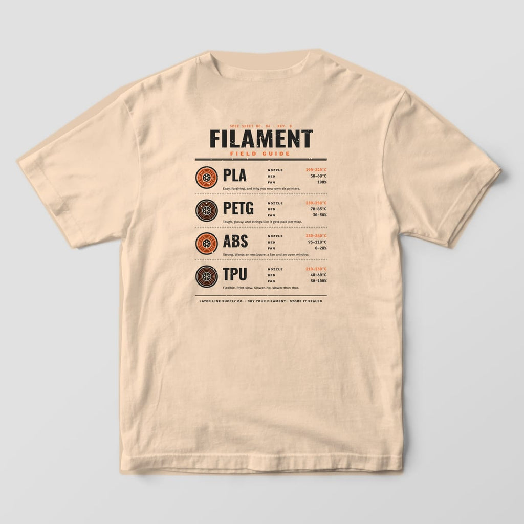 Back print on an Ivory Comfort Colors 1717 tee: "Filament Field Guide" spec sheet with spool icons and nozzle, bed and fan ranges for PLA, PETG, ABS and TPU, plus a one-line note for each