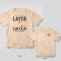 Layer by Layer 3D printing shirt shown back and front on Ivory Comfort Colors 1717: Giant "Layer by Layer" type made of horizontal layer stripes, the bottom word half printed under a working nozzle, with "Made, Not Bought." below