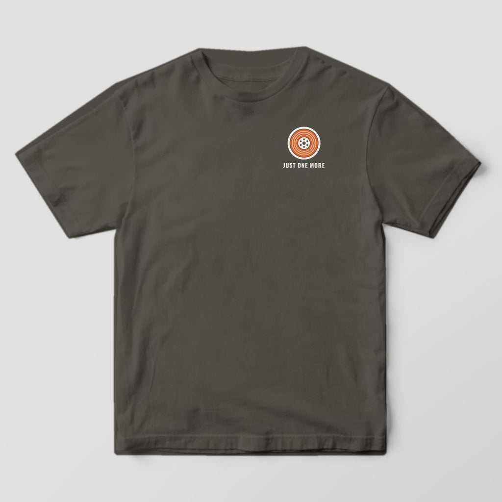 Front of the Pepper Comfort Colors 1717 tee showing the left-chest print: Small left-chest orange and off-white filament spool with "Just One More" below