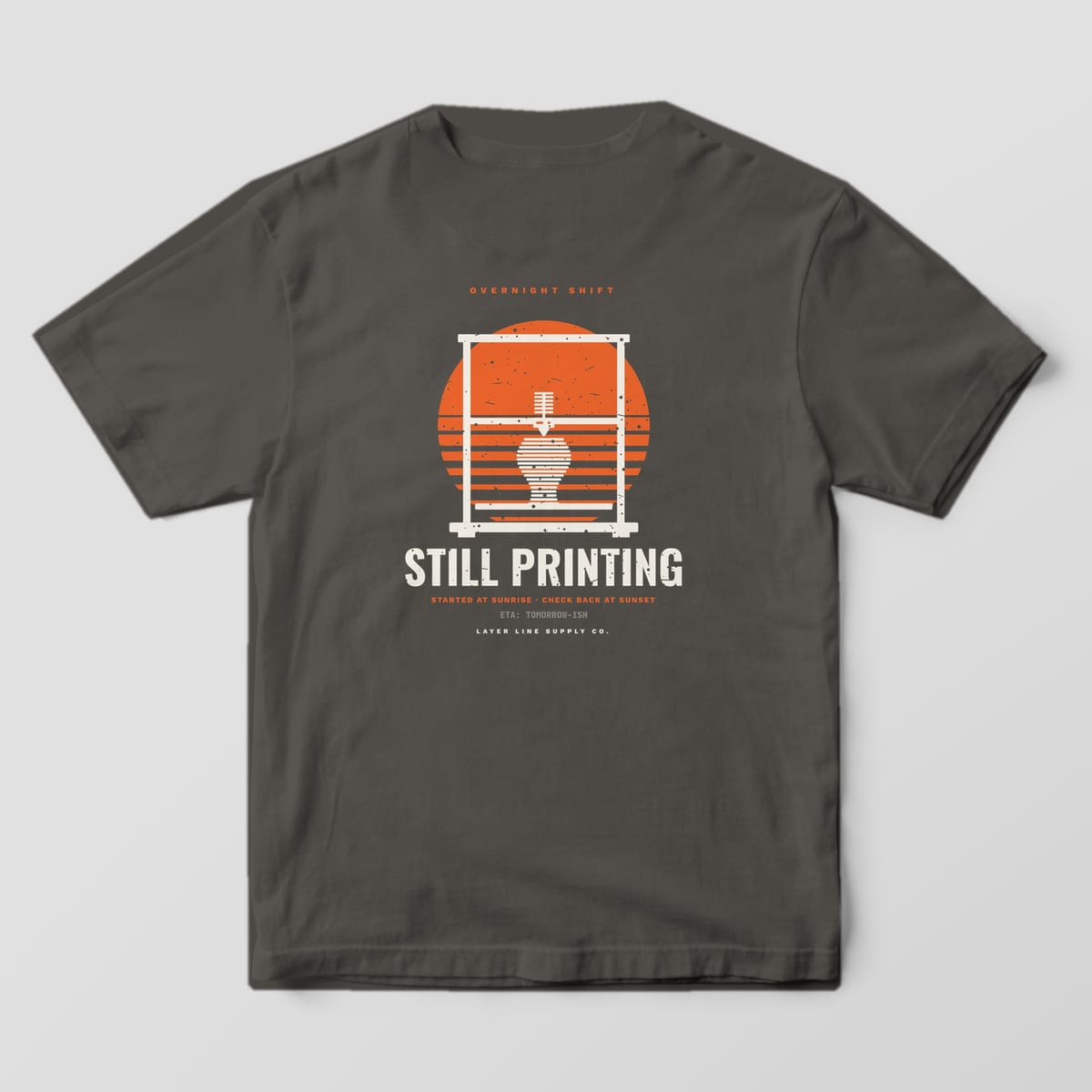 Back print on a Pepper Comfort Colors 1717 tee: "Overnight Shift" over a striped orange sunset framed by a printer gantry with a half-printed vase, "Still Printing" in bold below