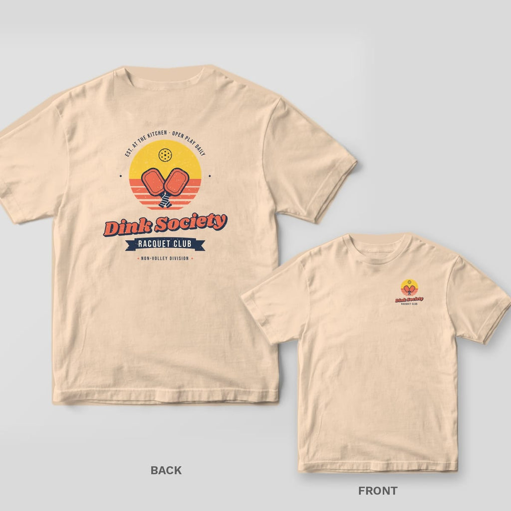 Dink Society Racquet Club pickleball shirt shown back and front on Ivory Comfort Colors 1717: Dink Society Racquet Club badge with crossed coral paddles over a striped yellow sunset