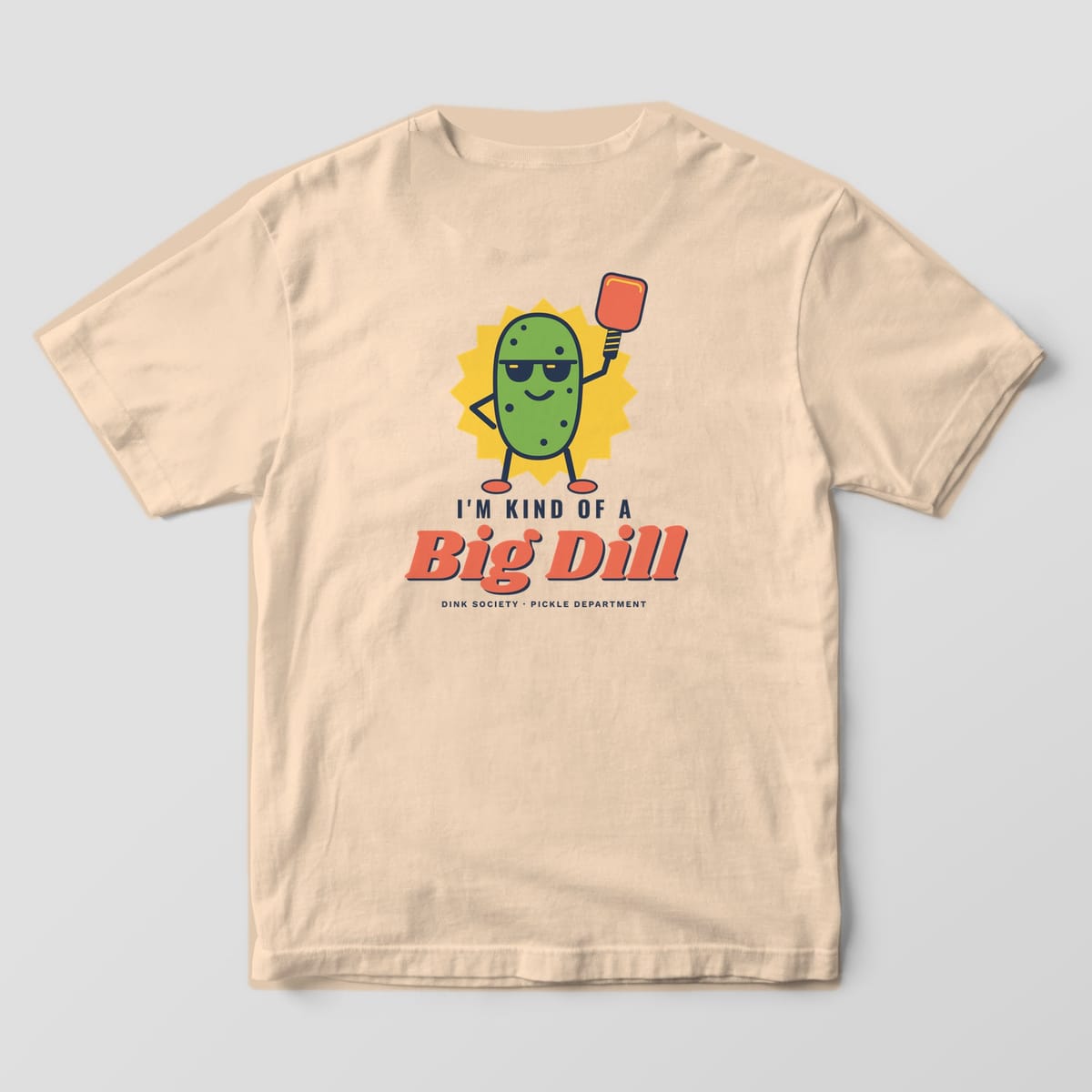 Back print on an Ivory Comfort Colors 1717 tee: Green pickle in sunglasses holding a coral paddle over a yellow burst with I'm Kind of a Big Dill text