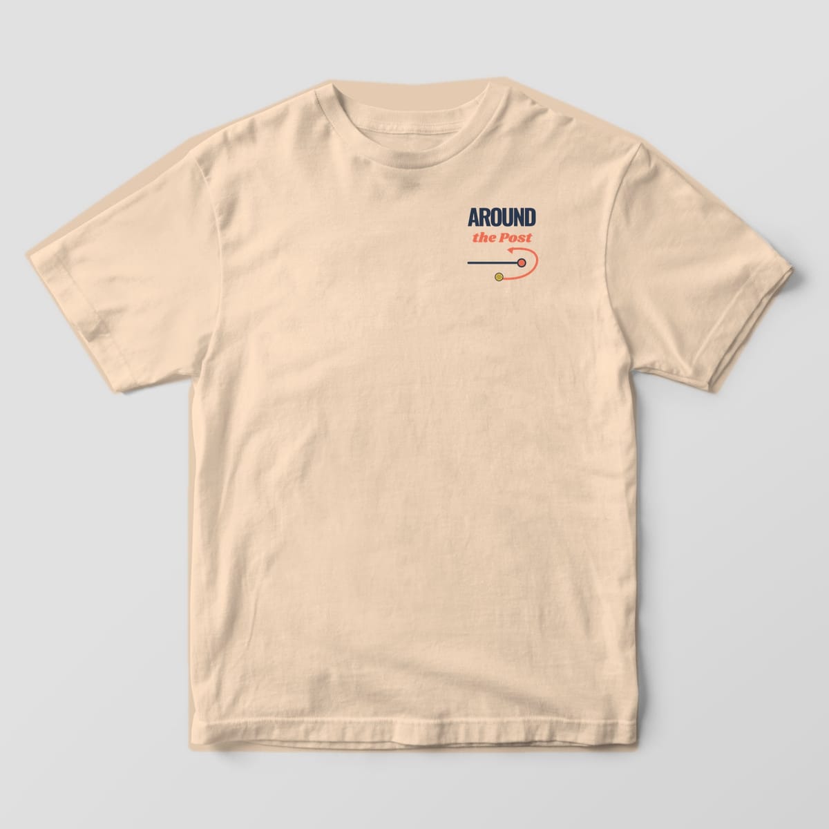 Front of the Ivory Comfort Colors 1717 tee showing the left-chest print: Left-chest type: "Around" in bold navy and "the Post" in coral script, over a net line, post and coral arrow curling a ball around it