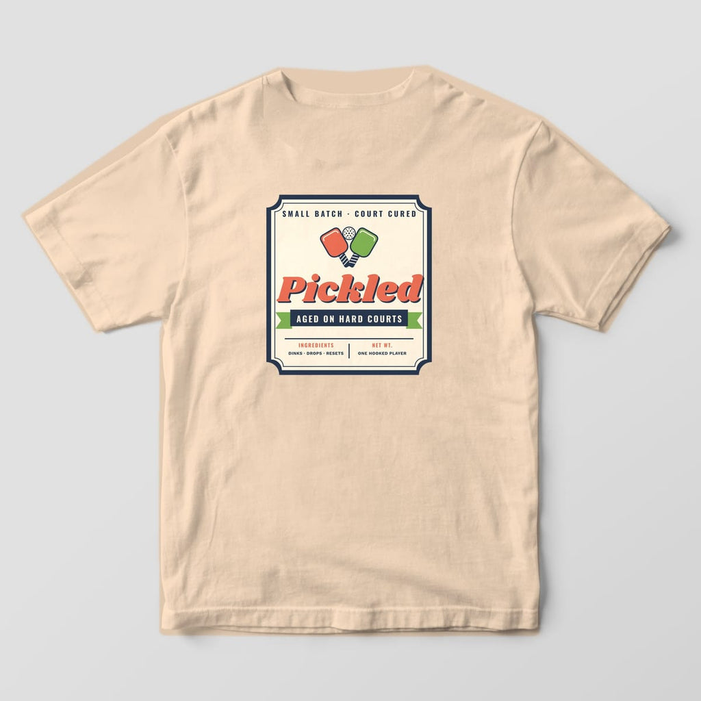 Back print on an Ivory Comfort Colors 1717 tee: Vintage pickle jar label reading Pickled, Aged on Hard Courts with crossed coral and green paddles