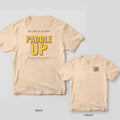 Paddle Up pickleball shirt shown back and front on Ivory Comfort Colors 1717: Stacked yellow block letters reading Paddle Up with coral and navy shadows