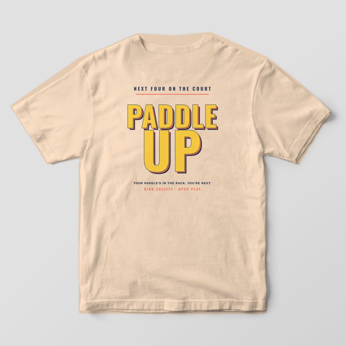 Back print on an Ivory Comfort Colors 1717 tee: Stacked yellow block letters reading Paddle Up with coral and navy shadows