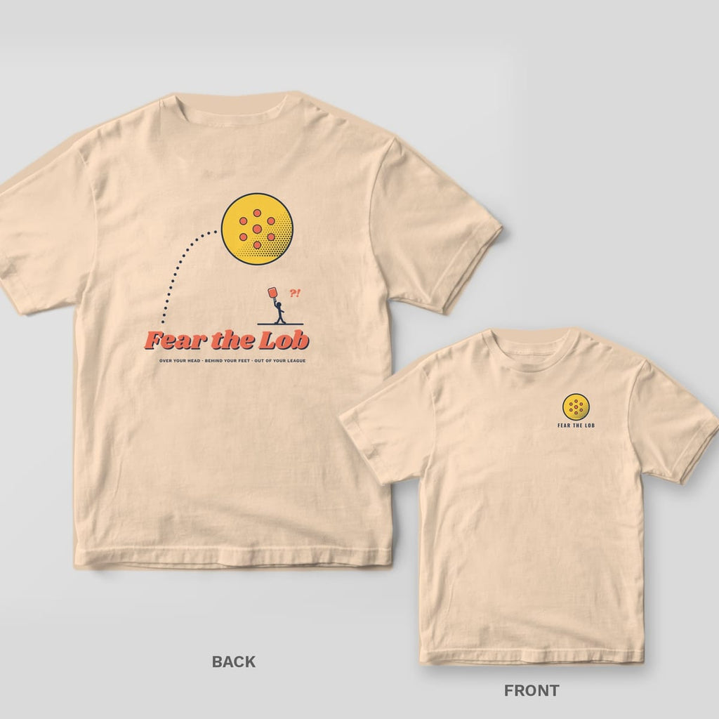 Fear the Lob pickleball shirt shown back and front on Ivory Comfort Colors 1717: Huge halftone pickleball sailing on a dotted arc over a tiny player under Fear the Lob script