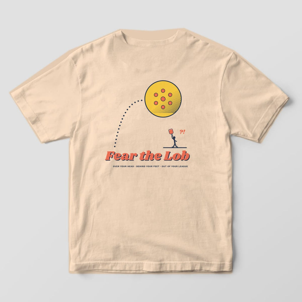 Back print on an Ivory Comfort Colors 1717 tee: Huge halftone pickleball sailing on a dotted arc over a tiny player under Fear the Lob script