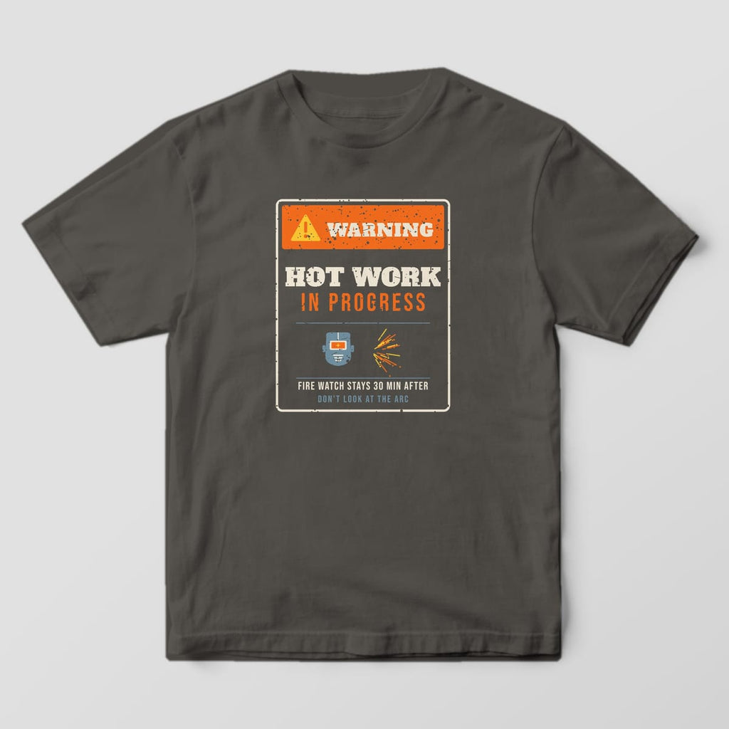 Front of the Pepper Comfort Colors 1717 tee showing the full-front print: Full-front distressed warning sign: orange "Warning" header, "Hot Work in Progress", a welding hood and sparks, "Fire Watch Stays 30 Min After" and "Don't Look at the Arc"
