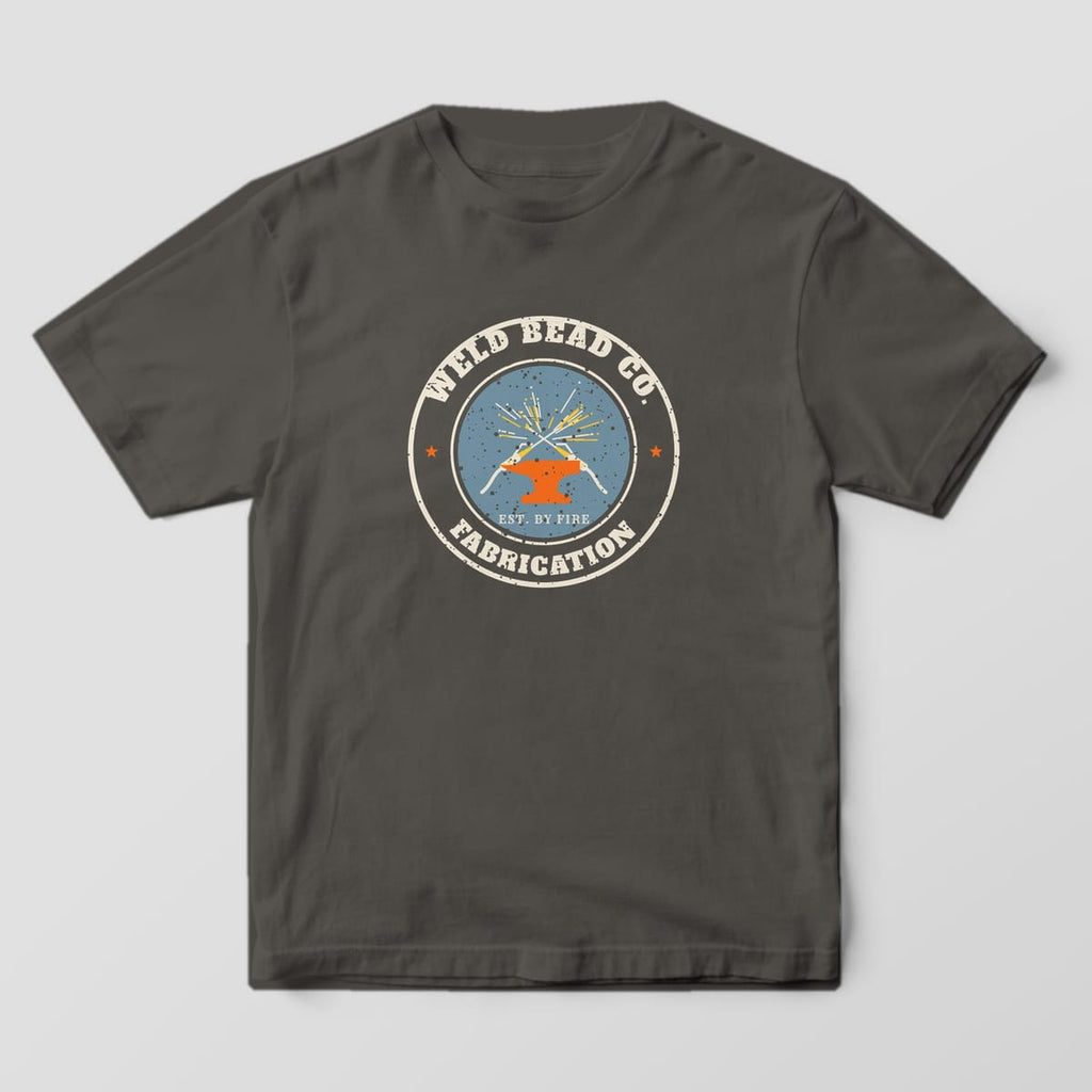 Front of the Pepper Comfort Colors 1717 tee showing the full-front print: Full-front distressed round badge with crossed welding guns, sparks, an anvil, "Weld Bead Co.", "Fabrication" and "Est. by Fire"