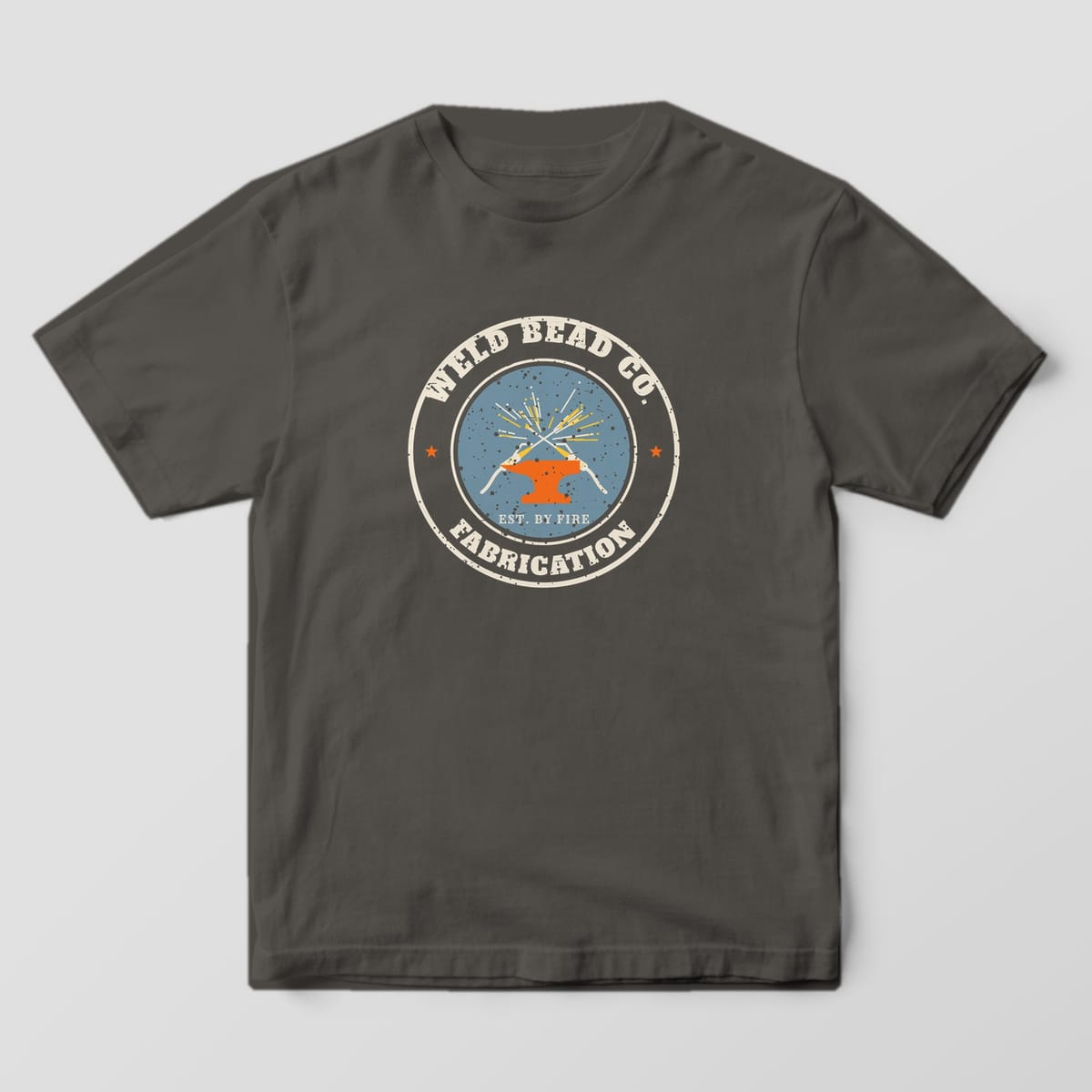 Front of the Pepper Comfort Colors 1717 tee showing the full-front print: Full-front distressed round badge with crossed welding guns, sparks, an anvil, "Weld Bead Co.", "Fabrication" and "Est. by Fire"
