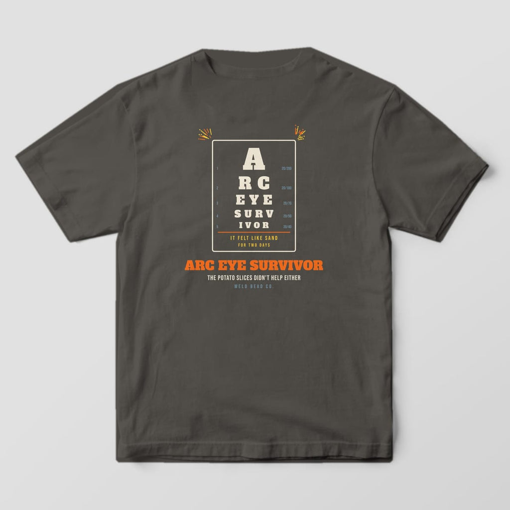 Back print on a Pepper Comfort Colors 1717 tee: An eye chart spelling "Arc Eye Survivor" with acuity numbers, "It Felt Like Sand for Two Days" and "The Potato Slices Didn't Help Either"