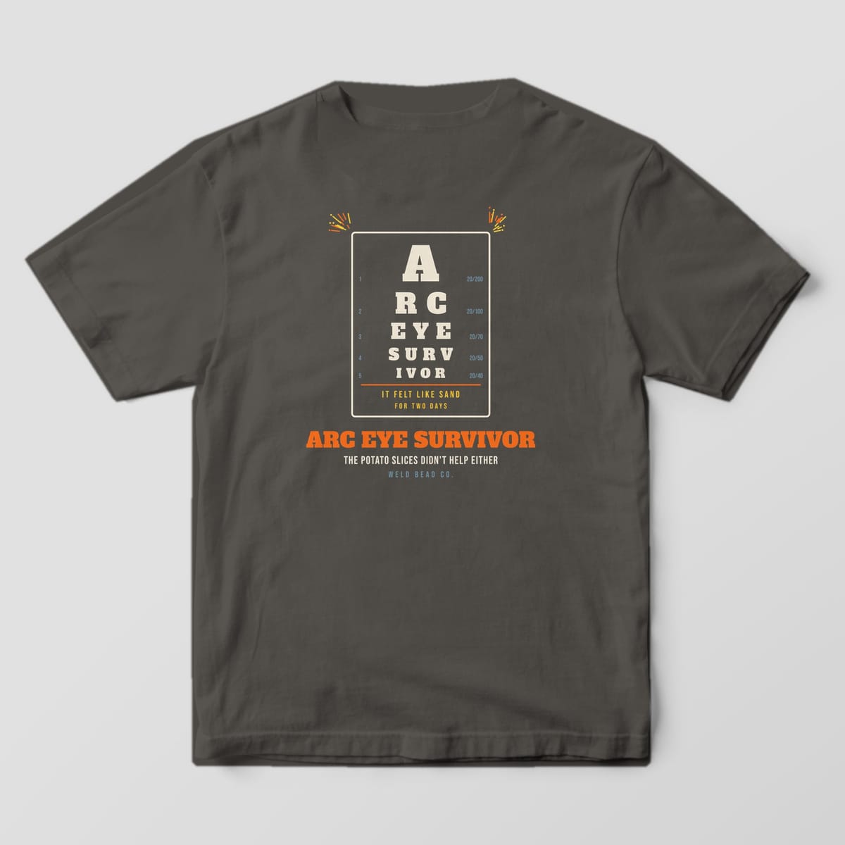 Back print on a Pepper Comfort Colors 1717 tee: An eye chart spelling "Arc Eye Survivor" with acuity numbers, "It Felt Like Sand for Two Days" and "The Potato Slices Didn't Help Either"