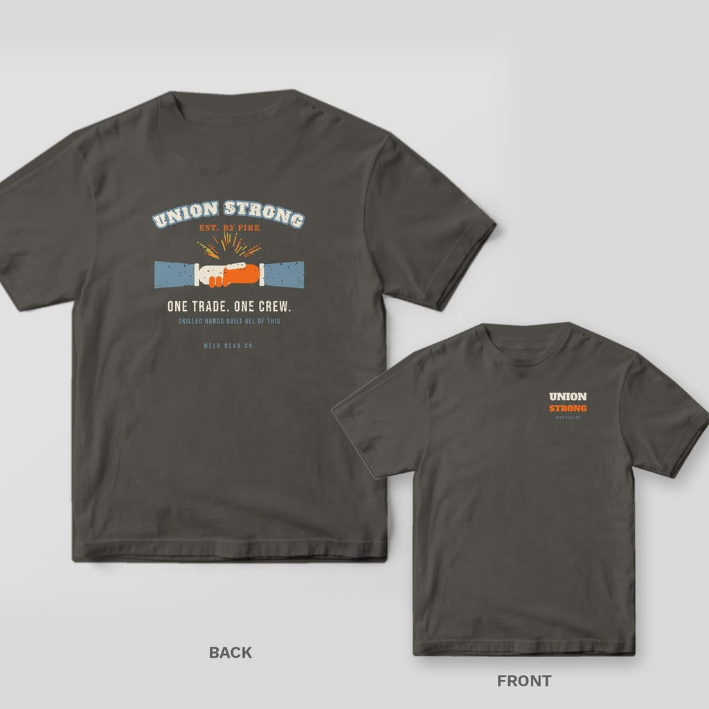 Union Strong welder shirt shown back and front on Pepper Comfort Colors 1717: Arched "Union Strong" over a gloved handshake with sparks, "One Trade. One Crew." and "Skilled Hands Built All of This"