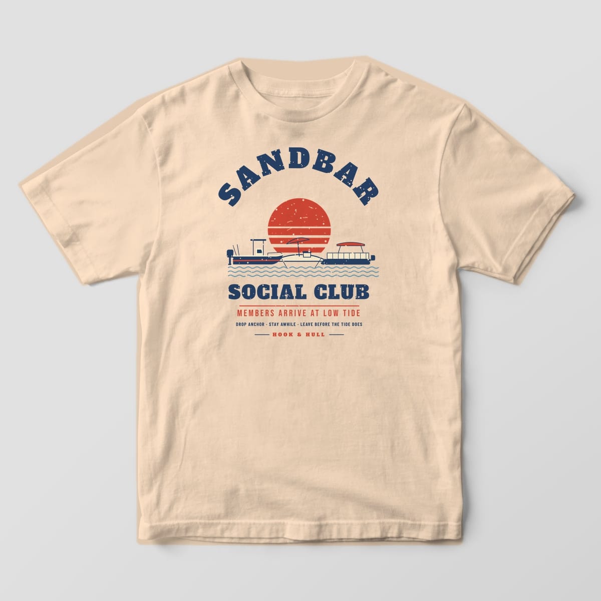 Front of an ivory Comfort Colors T-shirt with a full front print of two anchored boats at a sandbar under a striped sunset with the words Sandbar Social Club