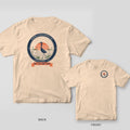 Back and front of an ivory Comfort Colors tee with a navy round heron badge and coral sunset