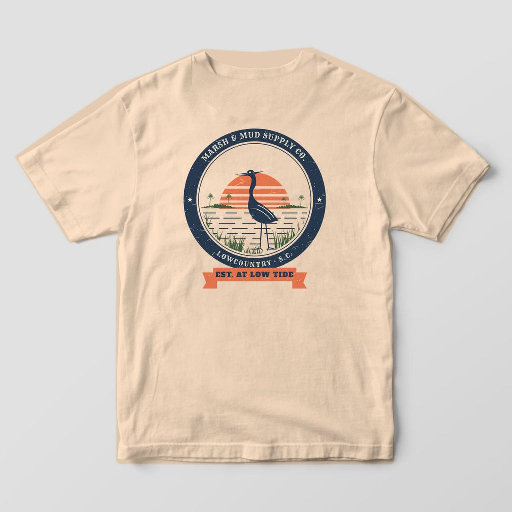 Back of an ivory Comfort Colors 1717 tee with a large round badge showing a heron in marsh grass and an Est. at Low Tide ribbon