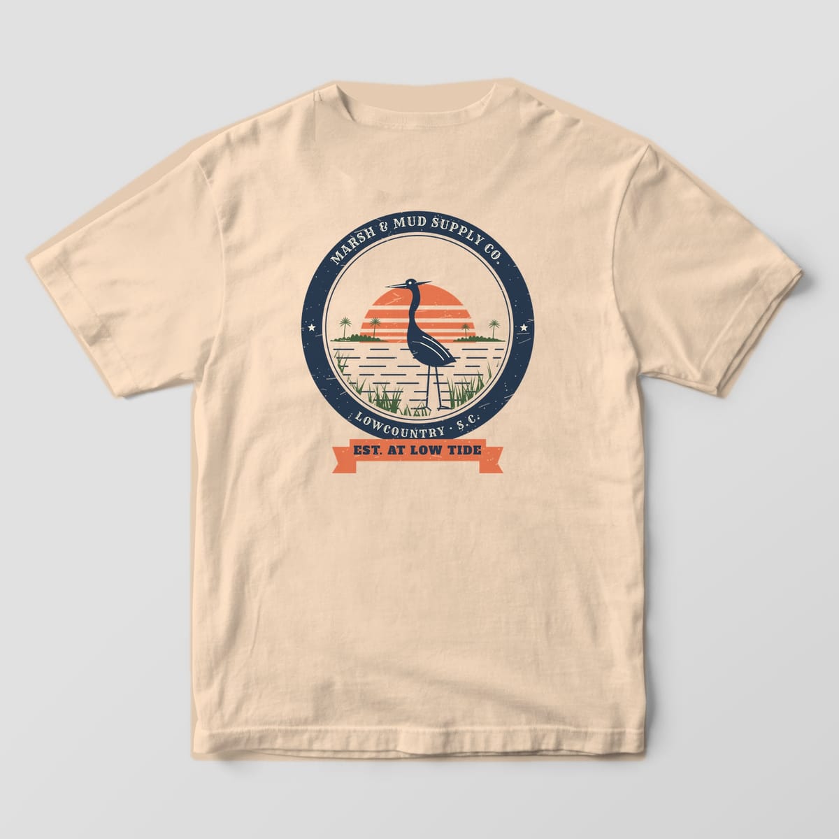 Back of an ivory Comfort Colors 1717 tee with a large round badge showing a heron in marsh grass and an Est. at Low Tide ribbon