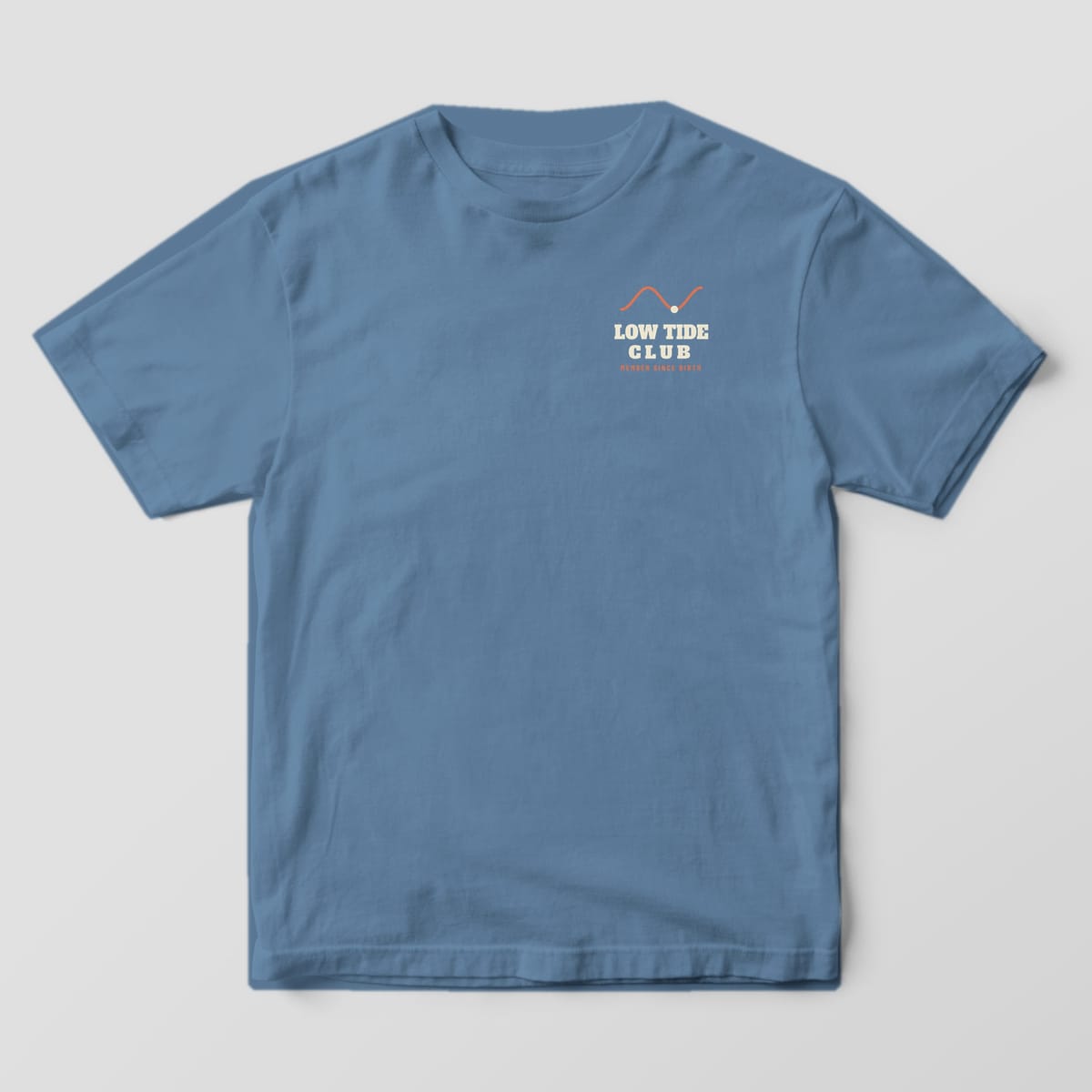 Front of a blue jean Comfort Colors 1717 tee with small Low Tide Club lettering and a coral tide curve on the left chest
