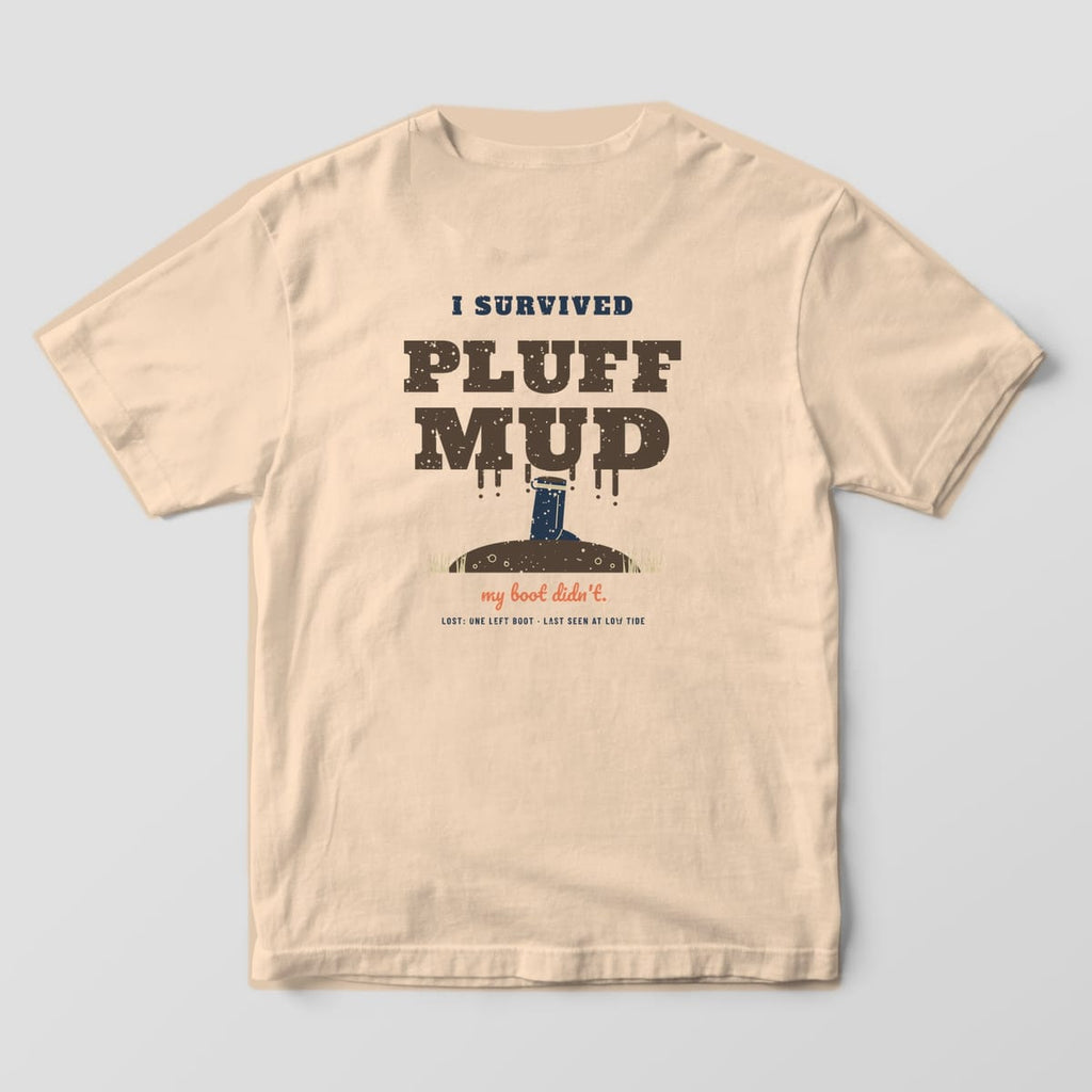 Back of an ivory Comfort Colors 1717 tee with dripping brown lettering and a navy rubber boot sunk in a mud mound