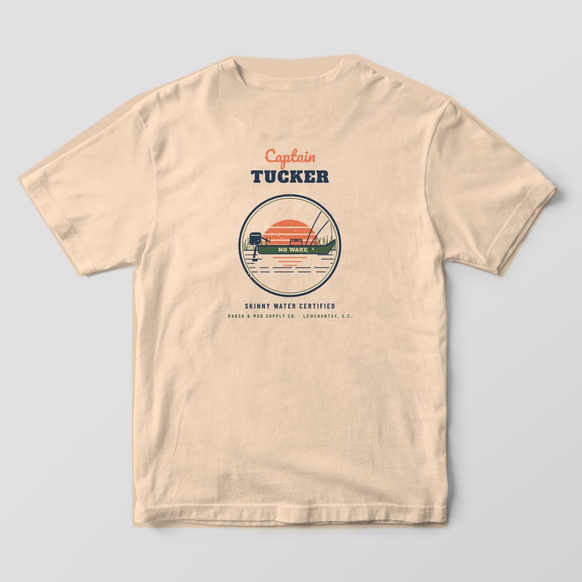 Back of an ivory Comfort Colors 1717 tee with Captain Tucker over a round badge of a green jon boat at sunset