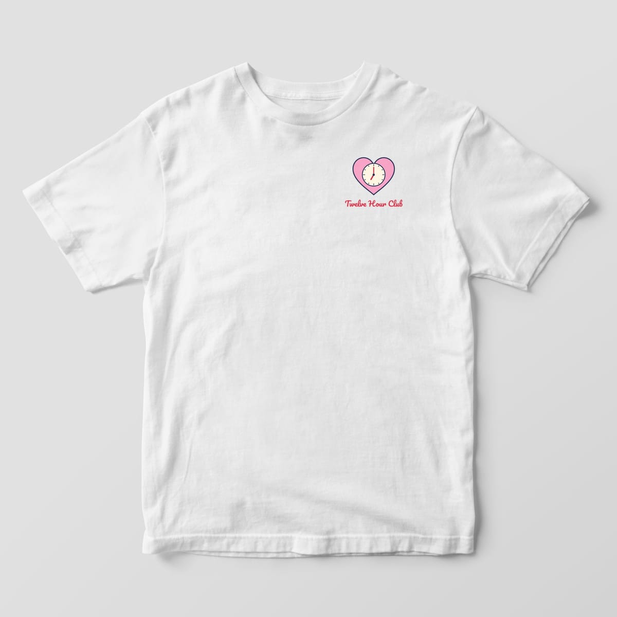 Front of a white Comfort Colors 1717 tee with a small pink heart clock and Twelve Hour Club script on the left chest