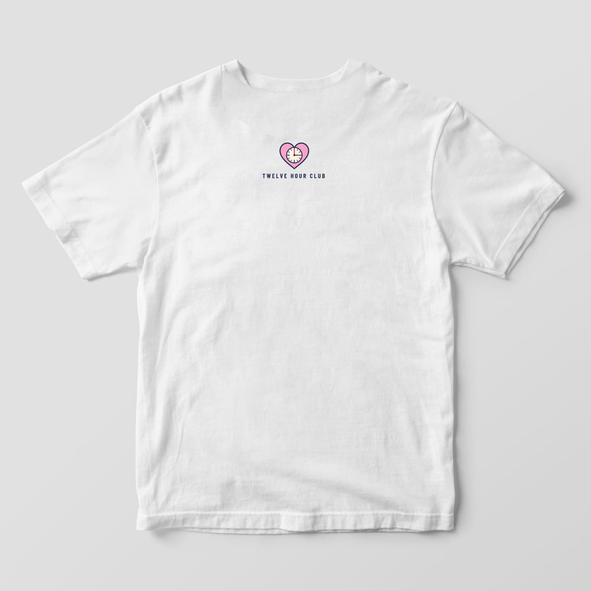 Back of a white Comfort Colors 1717 tee with a small pink heart clock and Twelve Hour Club below the collar