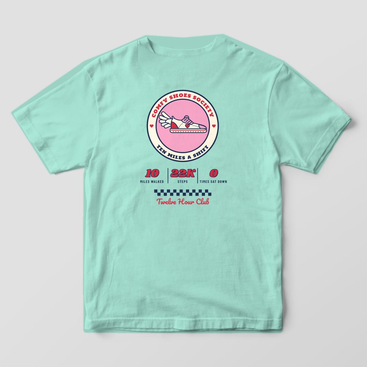 Back of a chalky mint Comfort Colors 1717 tee with a round Comfy Shoes Society badge, winged sneaker and shift stats