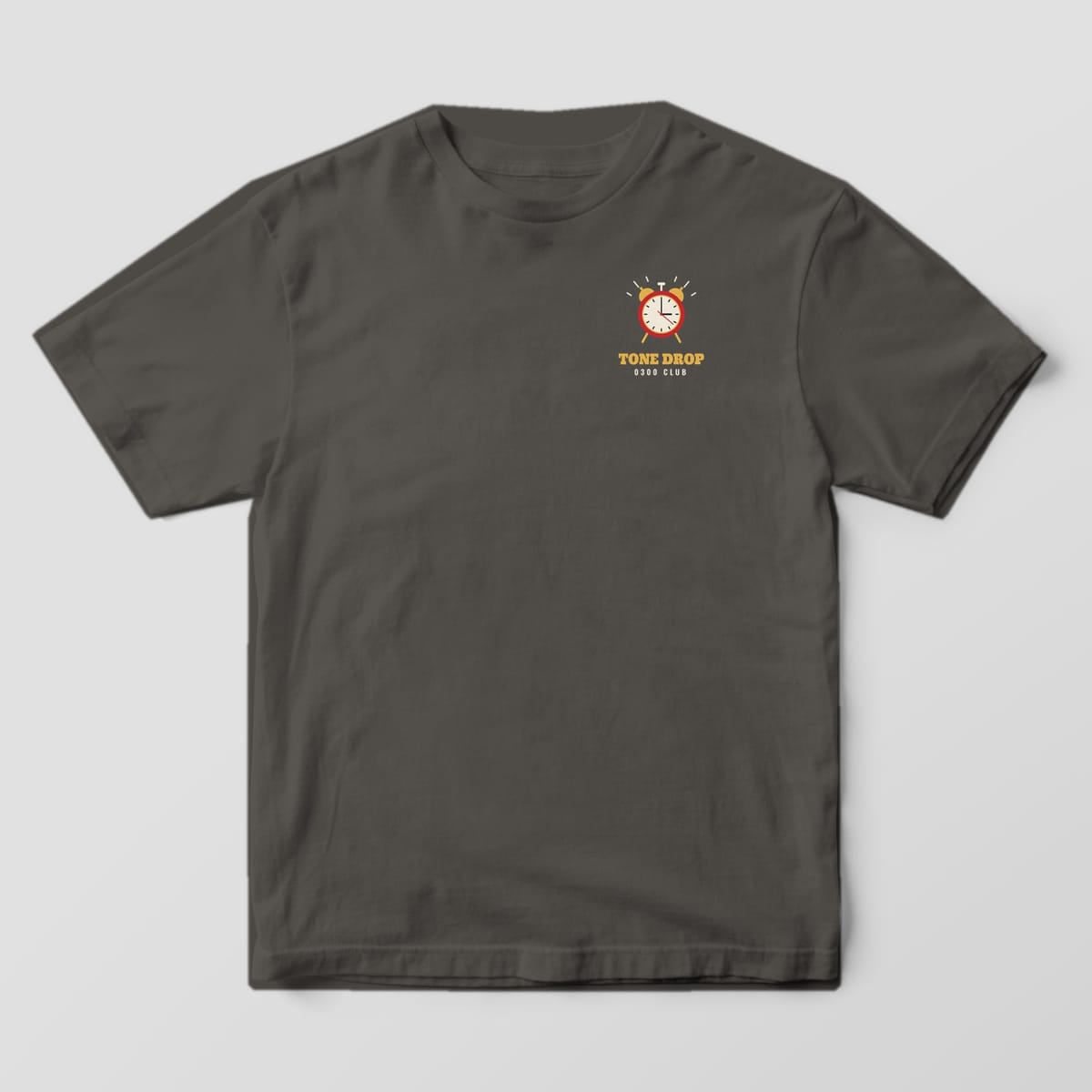 Front of a pepper Comfort Colors tee with a small alarm clock and Tone Drop 0300 Club on the left chest