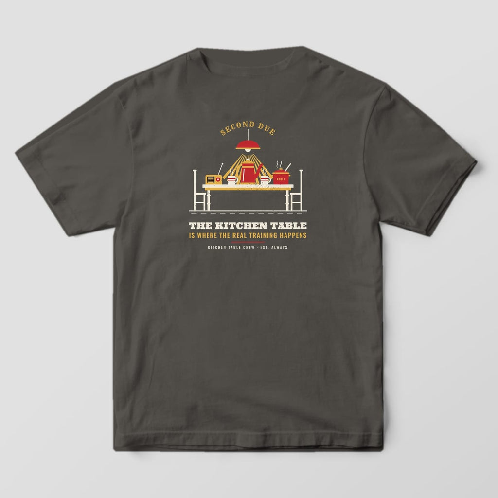Back of a pepper Comfort Colors tee with a kitchen table, percolator, mugs and chili pot under a lamp, plus the real training happens quote