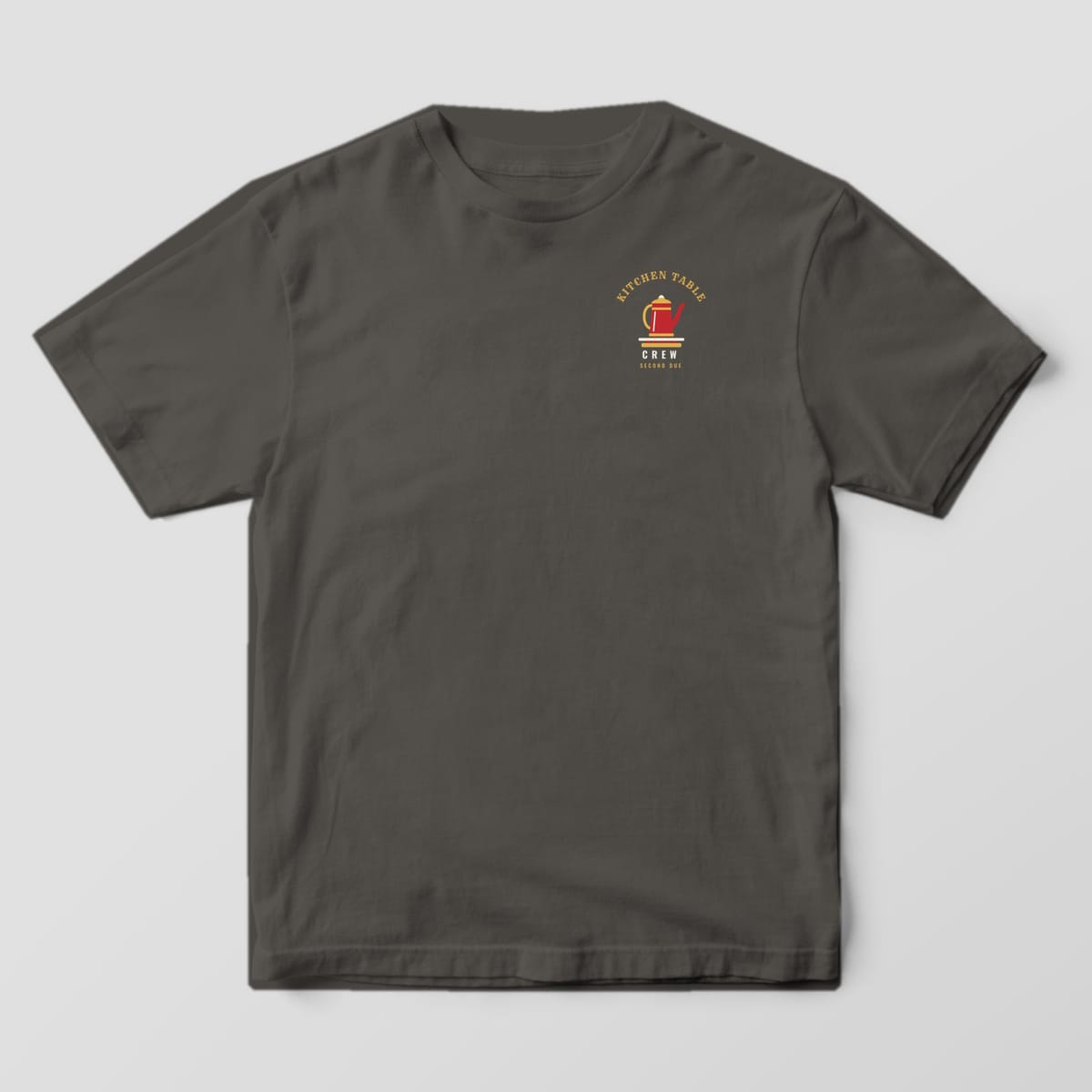 Front of a pepper Comfort Colors tee with a small red coffee percolator on a burner and Kitchen Table Crew text
