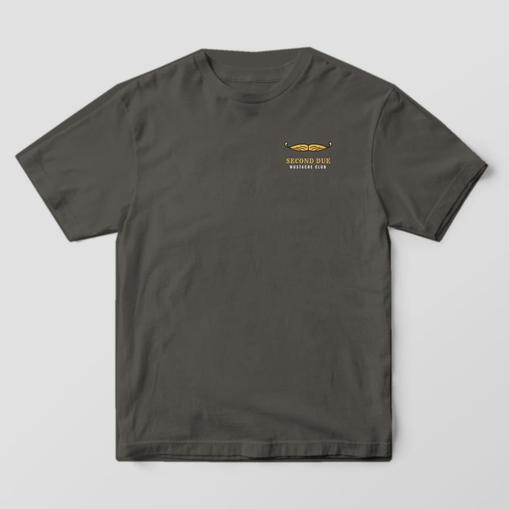 Front of a pepper Comfort Colors tee with a small gold handlebar mustache and Second Due Mustache Club on the left chest