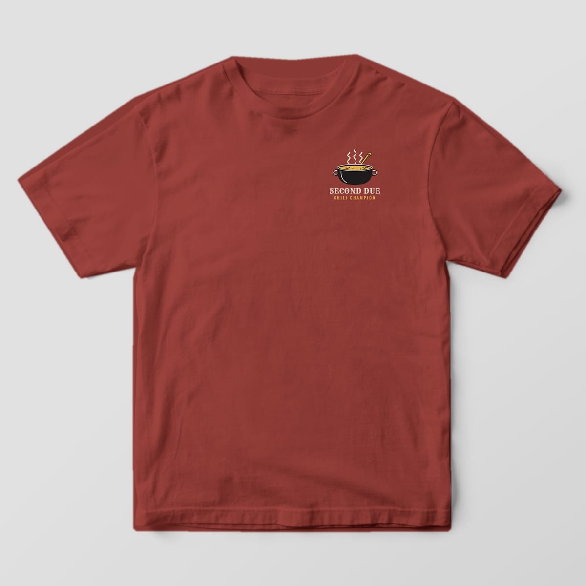 Front of a brick Comfort Colors tee with a small steaming chili pot and Second Due Chili Champion on the left chest