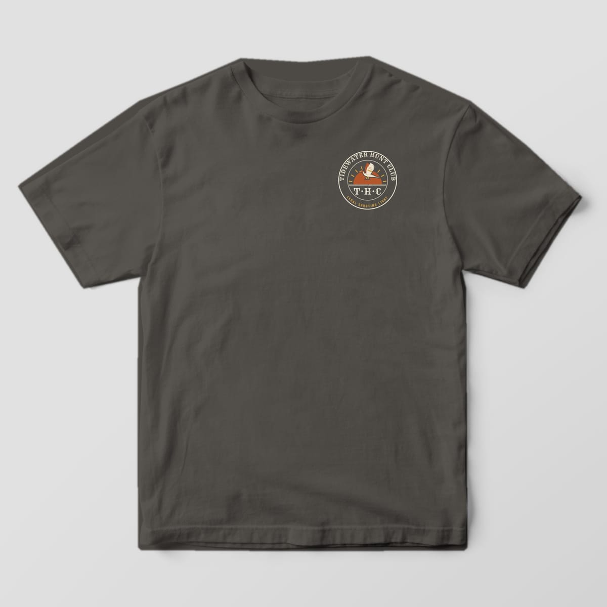 Front of the Pepper Comfort Colors 1717 tee showing the left-chest print: Left-chest round club seal with "Tidewater Hunt Club" arched on top, a pintail over a rising sun, "T·H·C" monogram and "Legal Shooting Light" on the rim