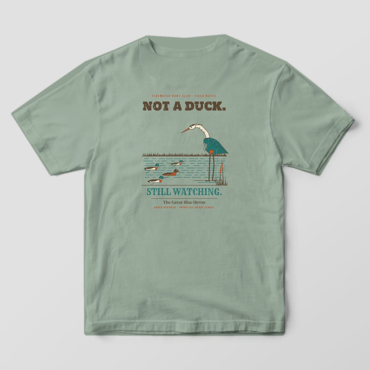Sage Bay Comfort Colors T-shirt back showing a great blue heron studying mallard decoys under the words Not a Duck