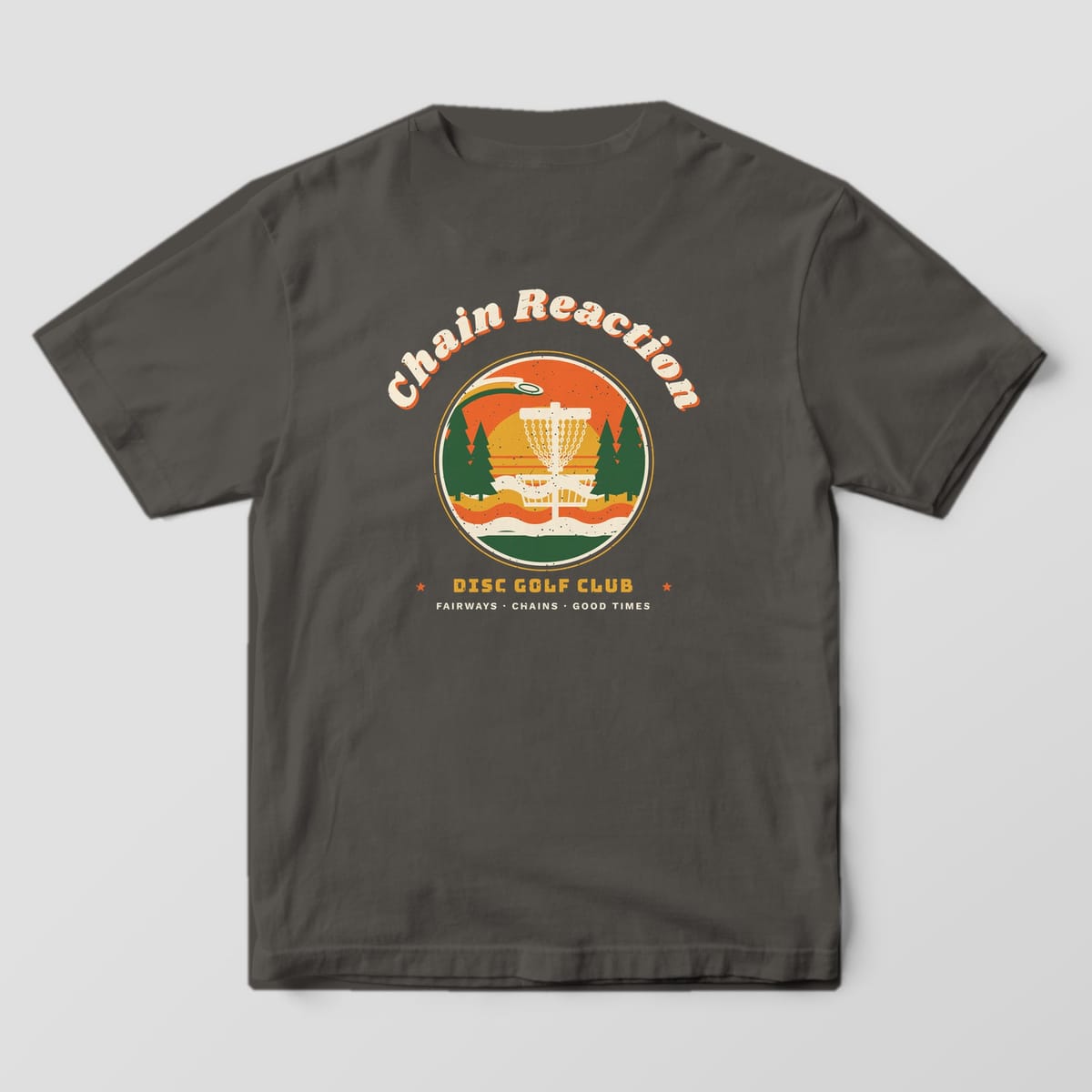 Back of a Pepper Comfort Colors 1717 tee printed with a round retro sunset badge with a disc golf basket and pines under arched Chain Reaction lettering.