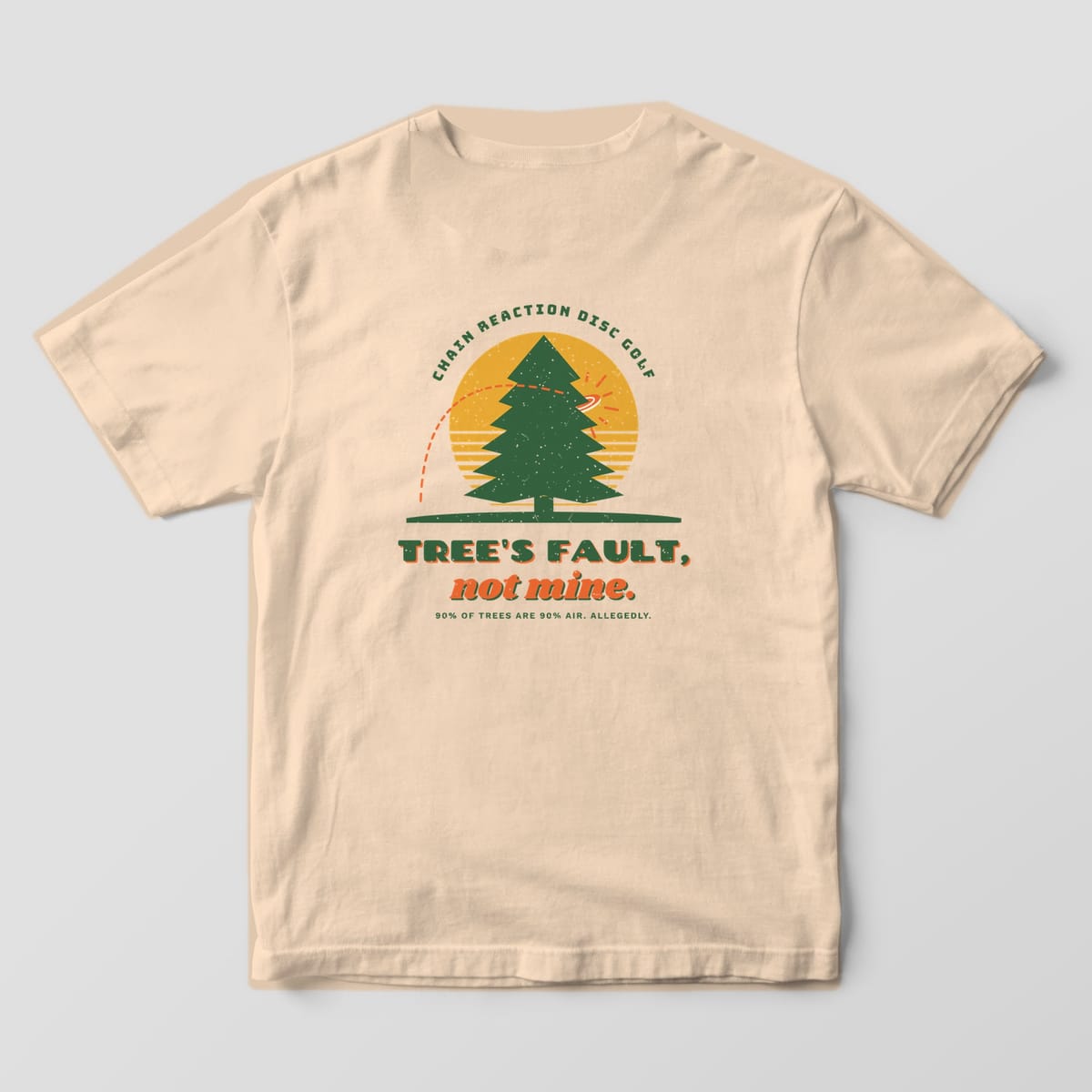 Back of an Ivory Comfort Colors 1717 tee printed with a forest-green pine against a mustard sun with a disc hitting it and the words Tree's Fault, not mine.